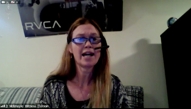 A Zoom screencap of a women with glasses and a headset mic speaking from what appears to be her living room couch. In the corner, it says D. McIlmoyle, Witness
